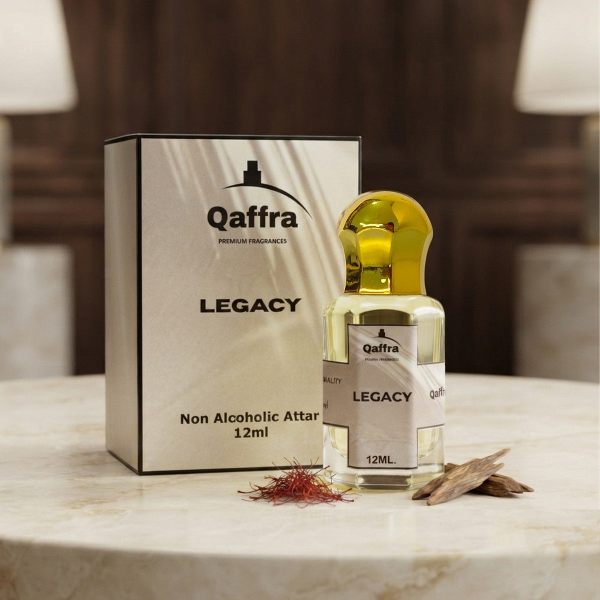 A bottle of Qaffra Legacy non-alcoholic attar perfume with a gold cap stands next to its white and black packaging box on a marble table, with saffron threads and dried petals in front.