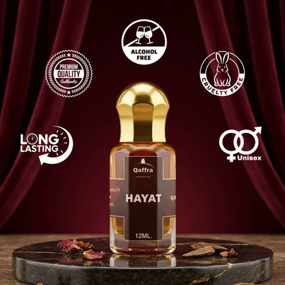 A 12ml bottle of Qaffra Hayat perfume oil with a shiny gold cap, displayed on a dark marble tray against a dark red curtain backdrop. The image includes several graphic badges highlighting product features like 'Premium Quality', 'Alcohol Free', 'Cruelty Free', 'Long Lasting', and 'Unisex'.